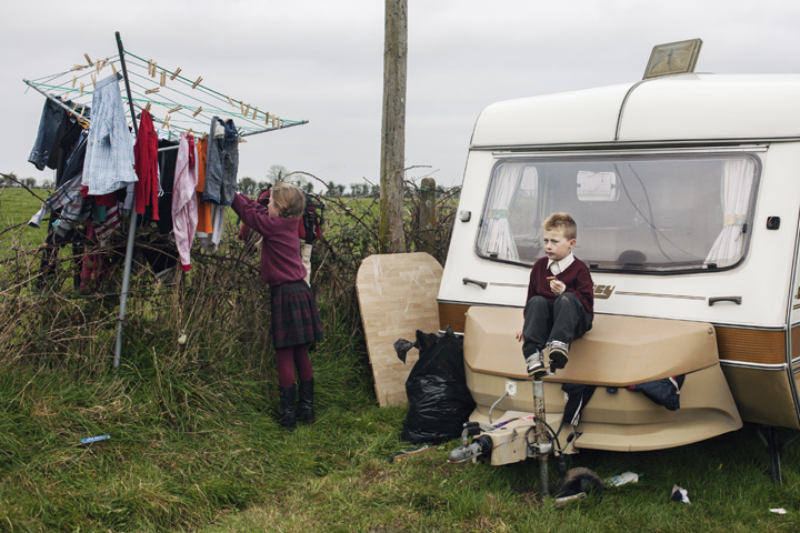 Pamela is hanging clothes on the dryer and Jimmy is sitting untop of the caravan.